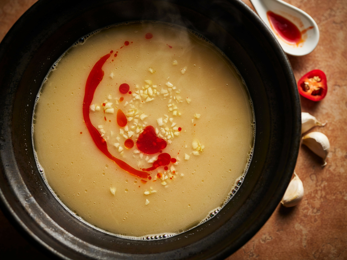 Creamy garlic ramen broth with a swirl of red chili oil