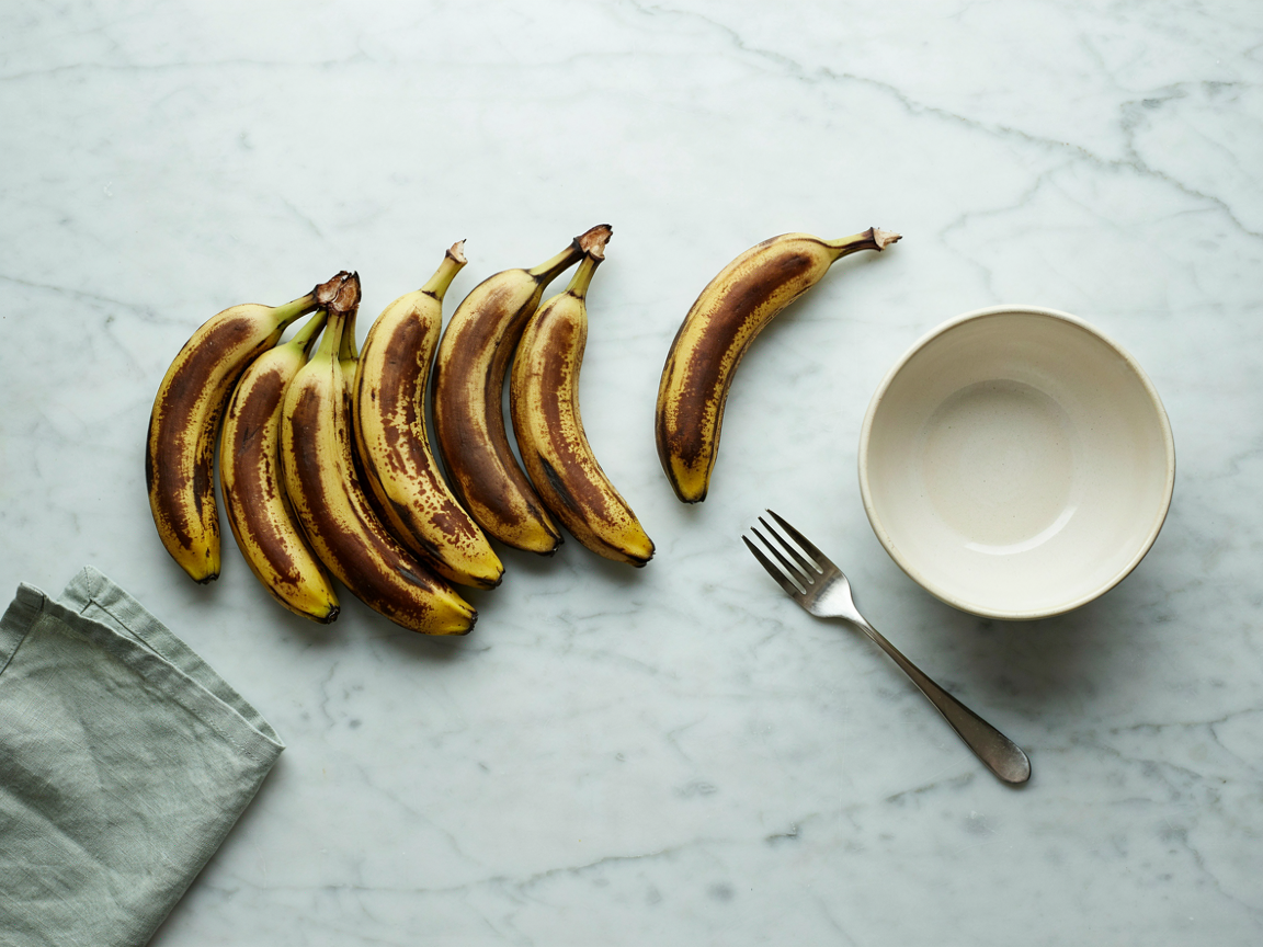 Heavily spotted overripe bananas on a light kitchen counter beside a mixing bowl